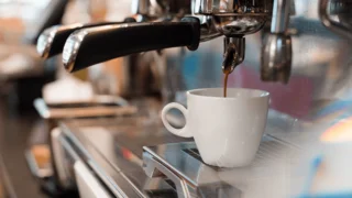 Siebträger-Kaffeemaschine mit Kaffeetasse, die gerade mit Kaffee befüllt wird