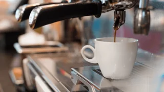 Siebträger-Kaffeemaschine mit Kaffeetasse, die gerade mit Kaffee befüllt wird
