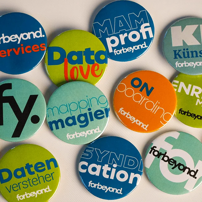 Verschiedene Buttons mit Motiven wie forbeyond Logo, Dam Chef, Moin, Mapping Magier, Enrichement