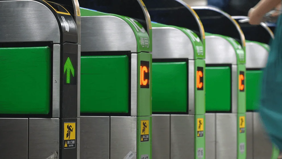 eine Reihe von Fahrkarten-Kontrollautomaten vor der eine Person steht