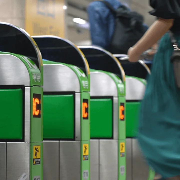 eine Reihe von Fahrkarten-Kontrollautomaten vor der eine Person steht