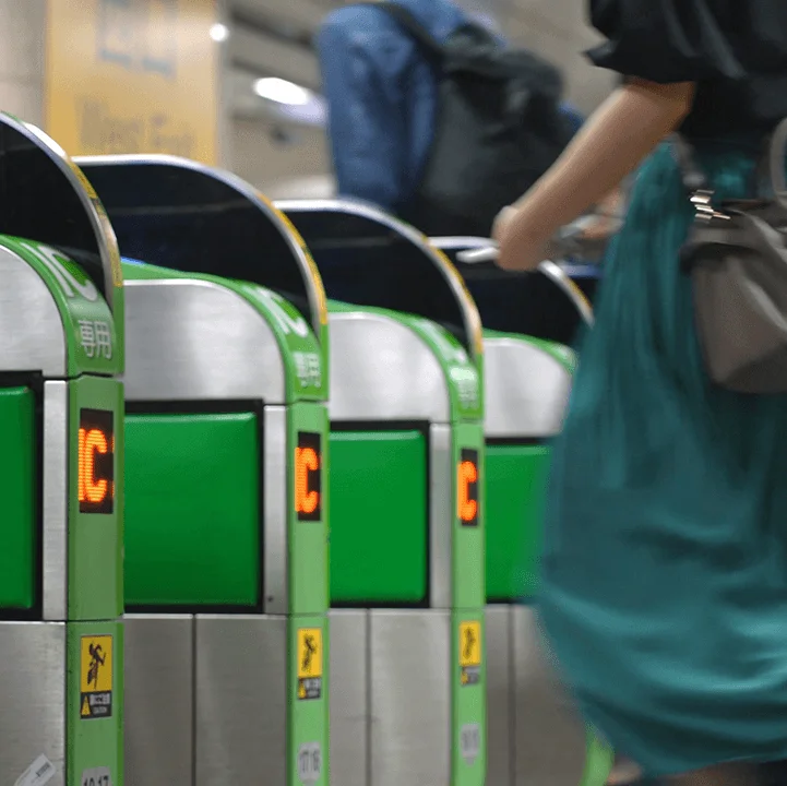 eine Reihe von Fahrkarten-Kontrollautomaten vor der eine Person steht