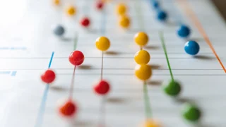 Farbige Stecknadeln auf einem Diagramm, die vernetzte Datenpunkte symbolisieren