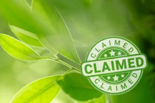 Unscharfe Blätter im Hintergrund. Im Vordergrund befindet sich ein Siegel mit der Aufschrift "Claimed"