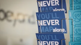Kartenständer mit Postkarten mit Schriftzug: You`ll never map alone und forbeyond Schriftzug im Hintergrund
